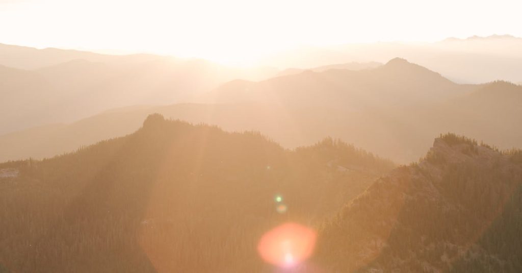 Breathtaking sunrise over Mount Rainier showcasing misty mountains and vibrant sunrays.